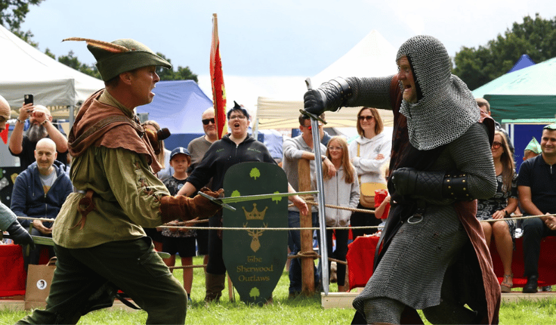 Photo of Robin Hood duelling with swords opposite a medieval knight.